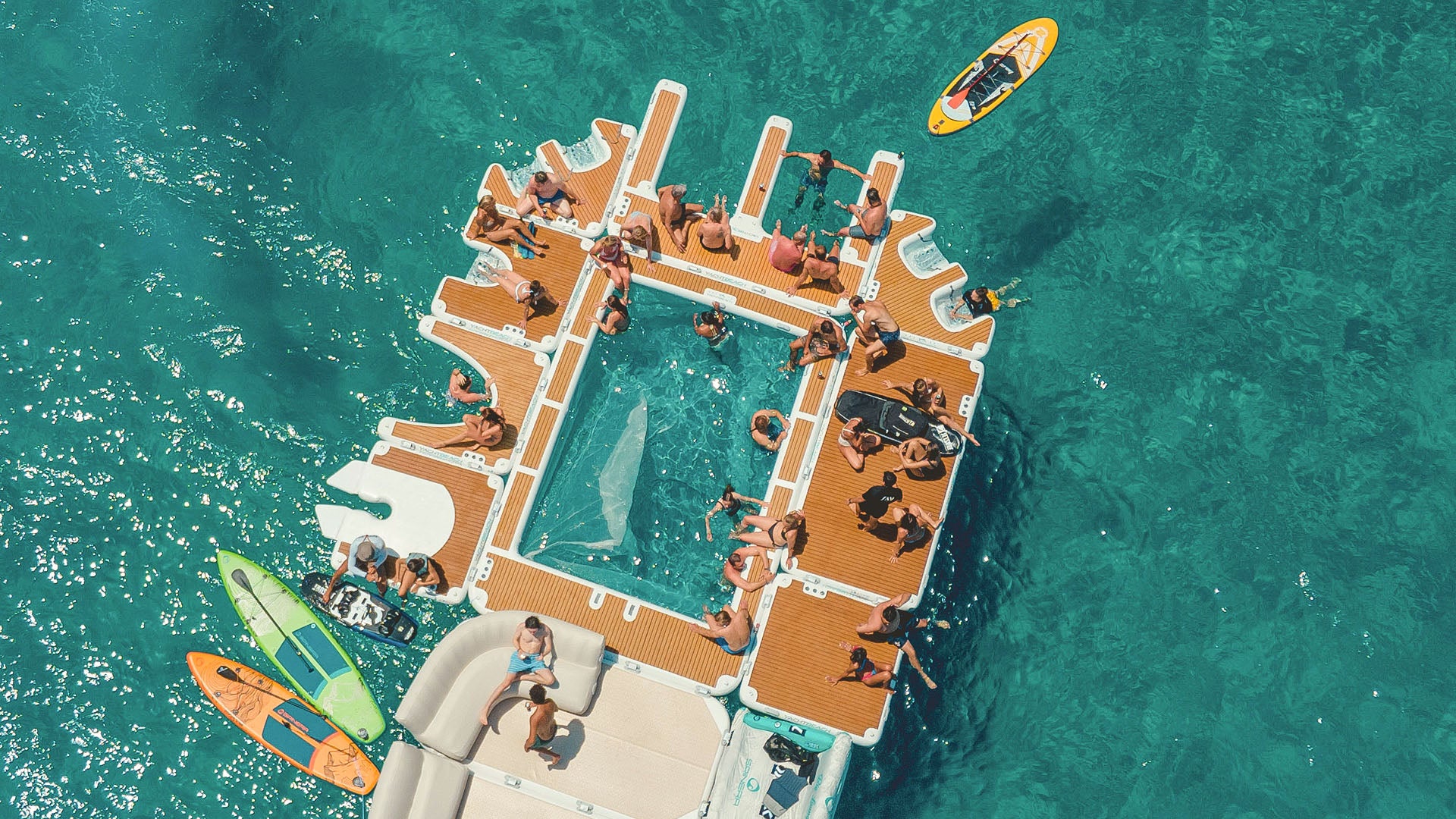 Der Yachtbeach Luxury Pool auf dem Wasser ist mit anderen Yachtbeach verbunden. Viele Menschen haben es sich darauf in ihren Badeanzügen bequem gemacht.