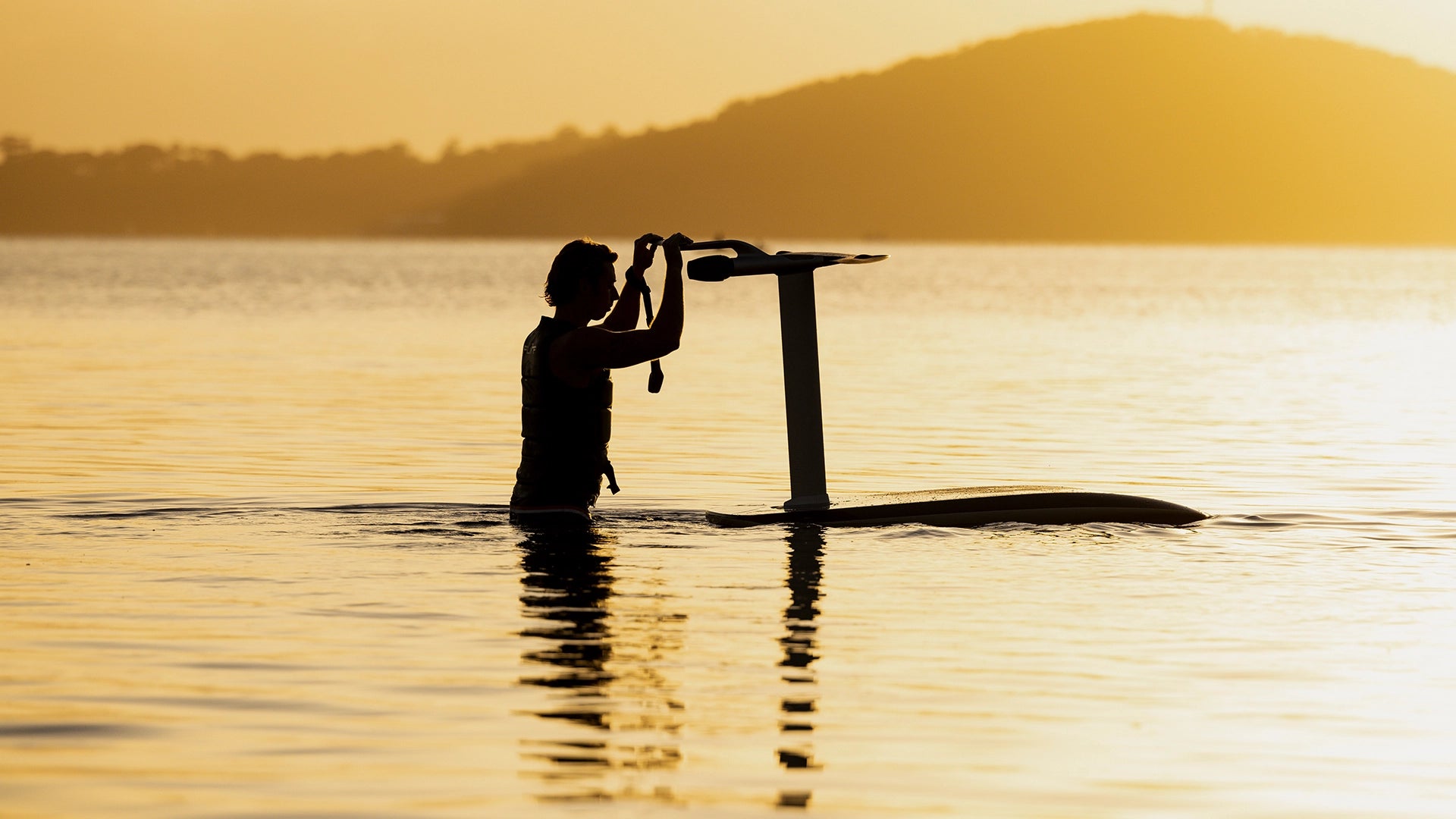 Person, die ein fliteboard Wasser hält, mit Sonnenuntergang im Hintergrund