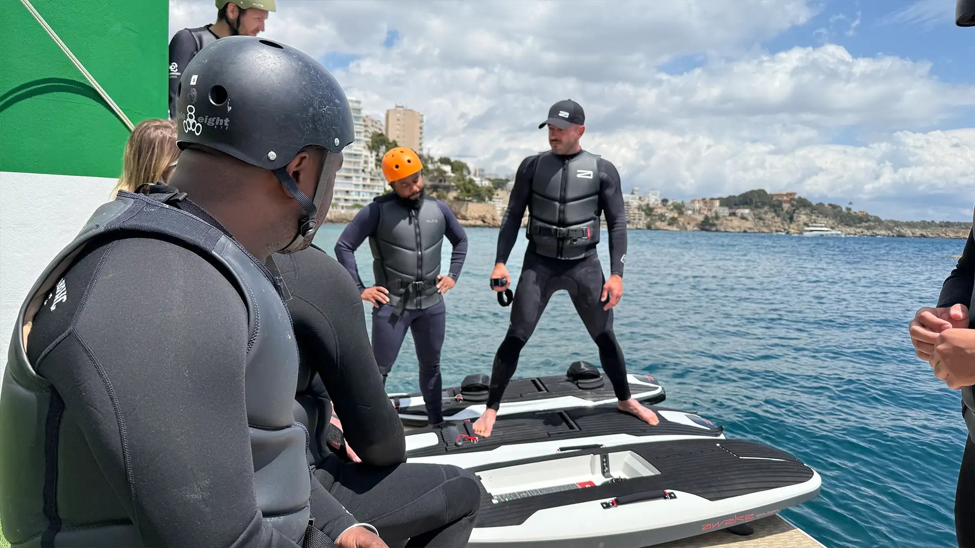 Personen in Neoprenanzügen und Helmen bereiten sich auf eine Session mit Awake Jetboards vor.