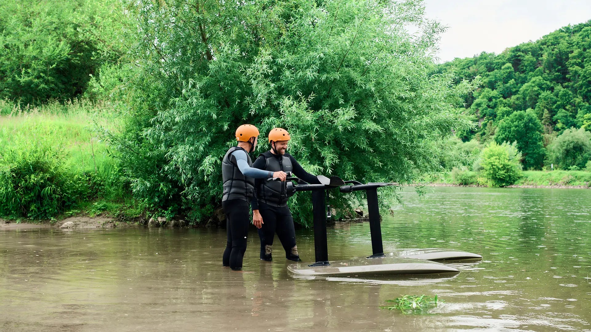 Zwei Personen stehen neben ihren Fliteboards in einem Fluss in Deutschland.