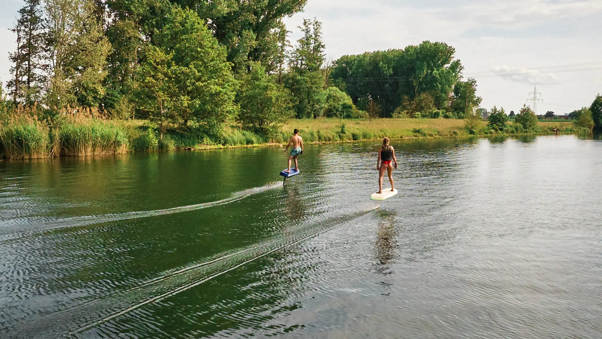 Zwei Personen stehen neben ihren Fliteboards in einem Fluss in Deutschland.