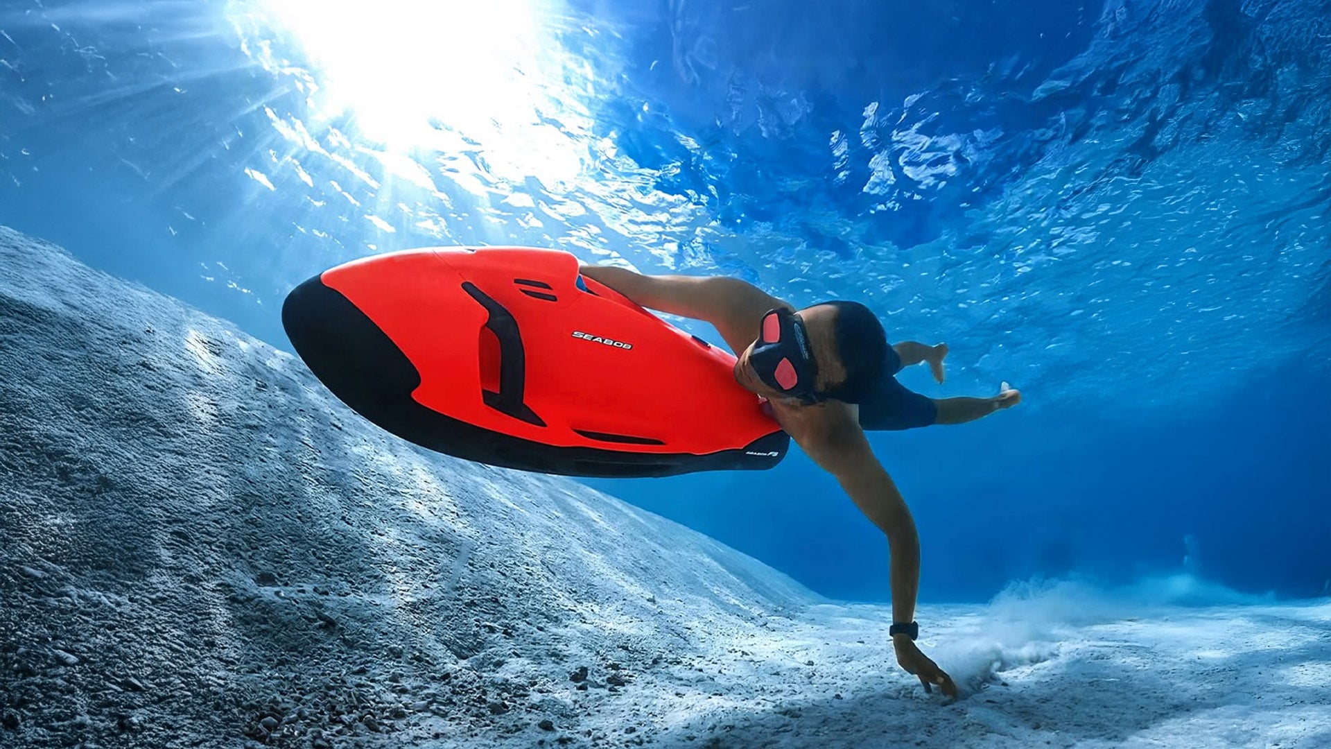 Ein Mann taucht mit einem roten Seabob.