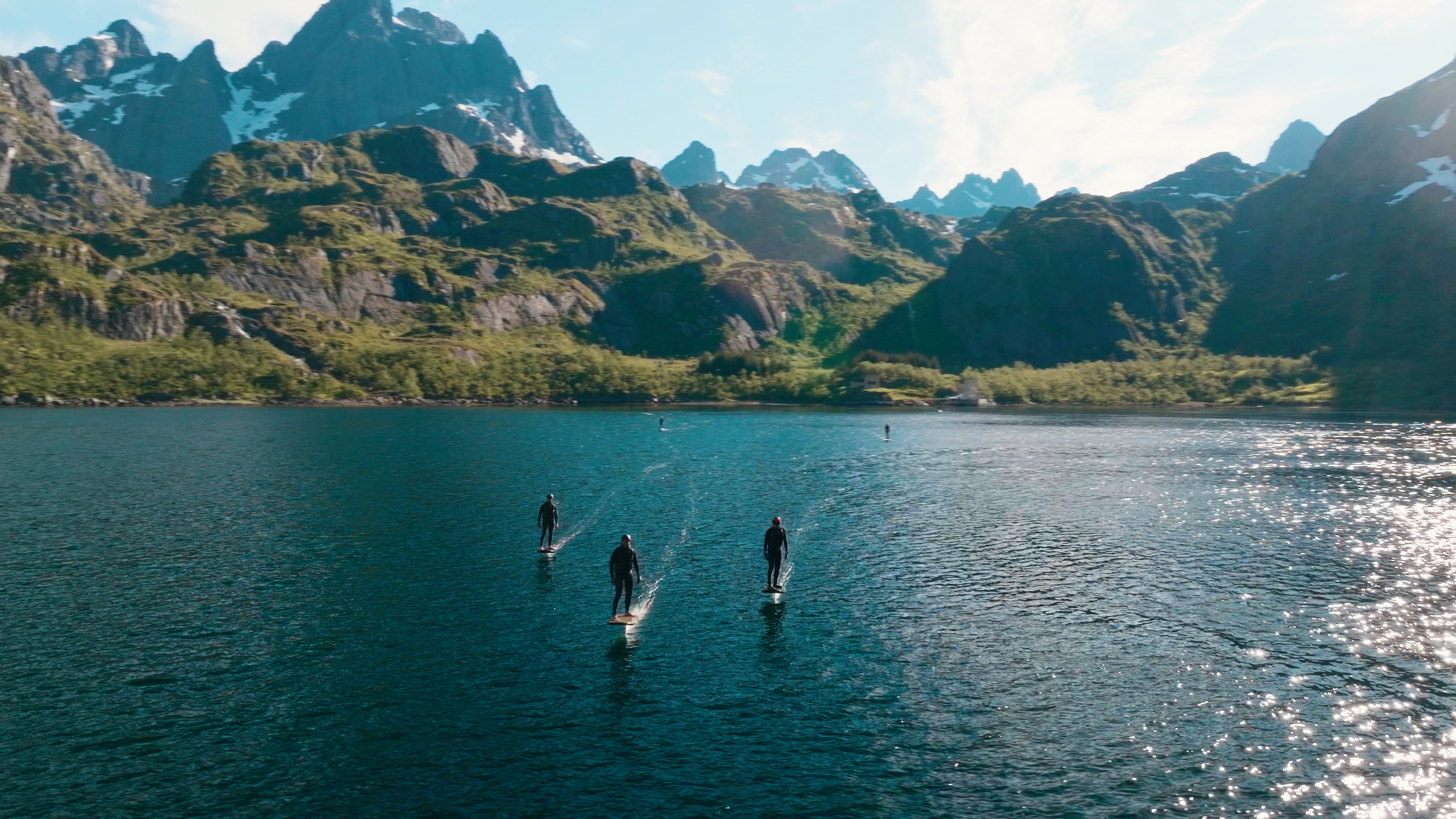 Mitten in Norwegen sind 5 Personen auf einem fliteboard auf dem Wasser unterwegs, mit mächtigen Bergen im Hintergrund.
