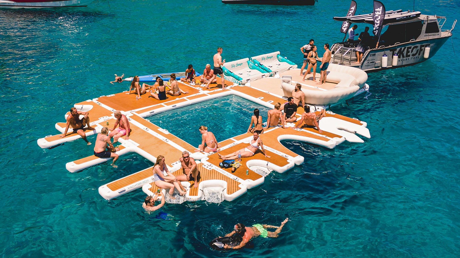 Der Yachtbeach Luxury Pool auf dem Wasser ist mit anderen Yachtbeach verbunden. Viele Menschen haben es sich darauf in ihren Badeanzügen bequem gemacht.