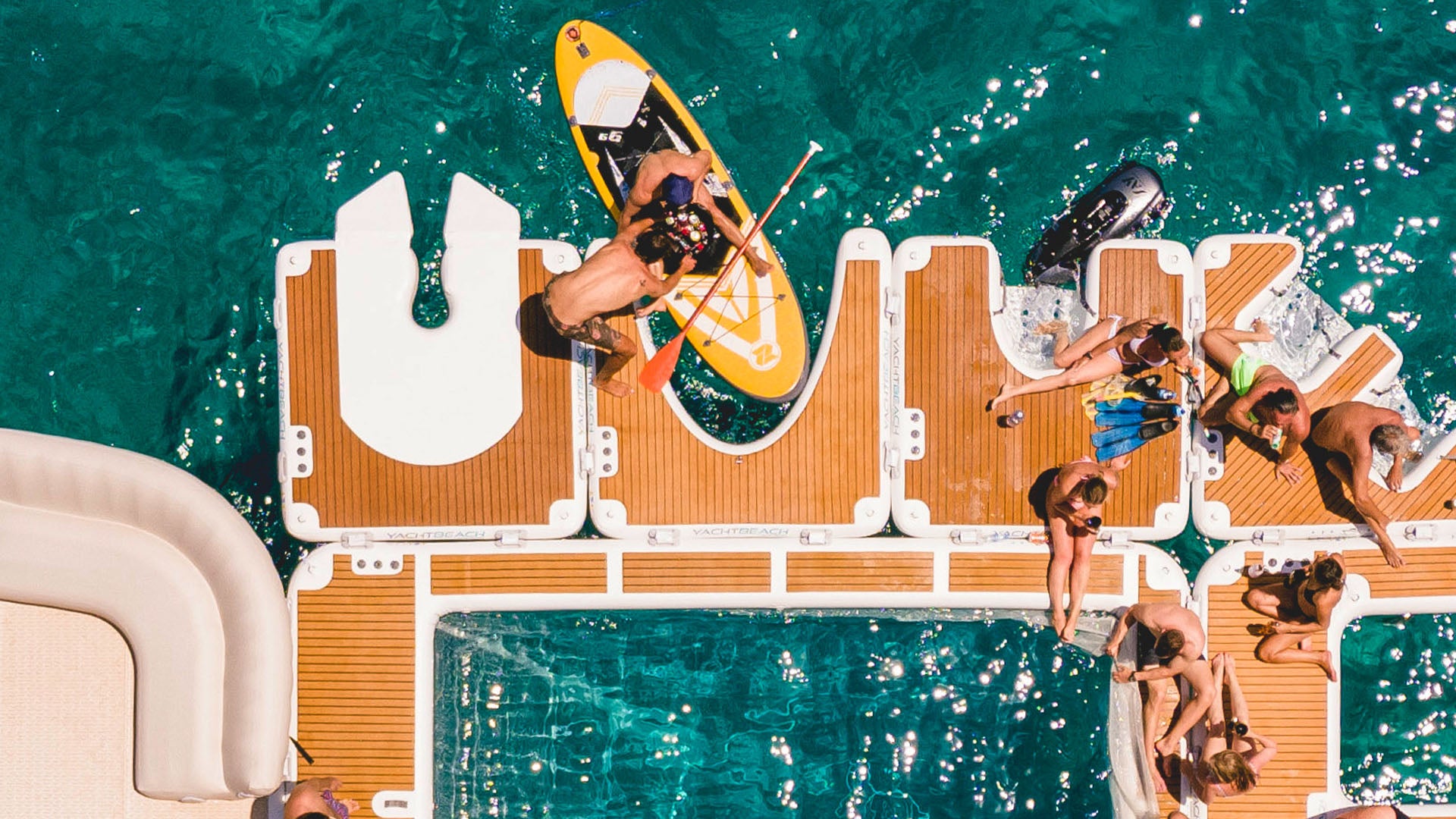 Der Yacht Beach Jet-Ski Single Version ist an anderen Plattformen befestigt, und die Leute sitzen auf ihnen im Wasser.