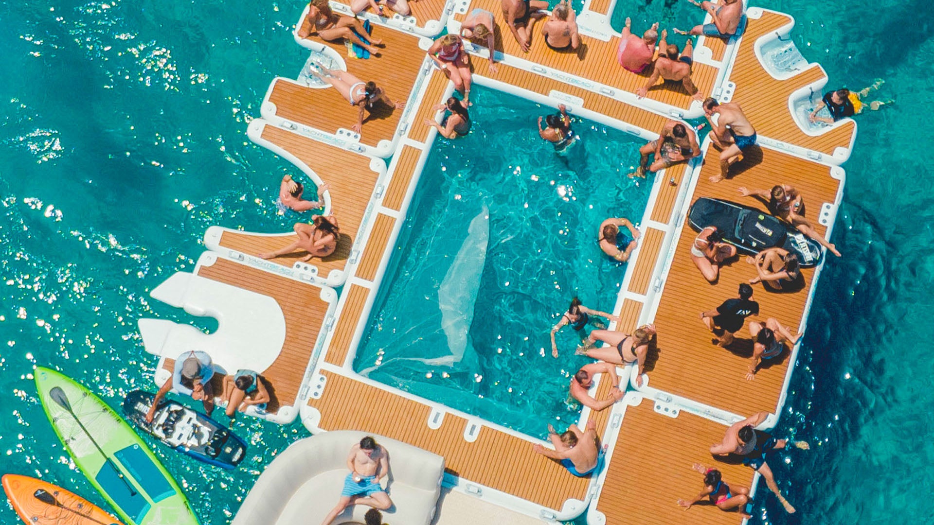 Der Yacht Beach Jet-Ski Single Version ist an anderen Plattformen befestigt, und die Leute sitzen auf ihnen im Wasser.