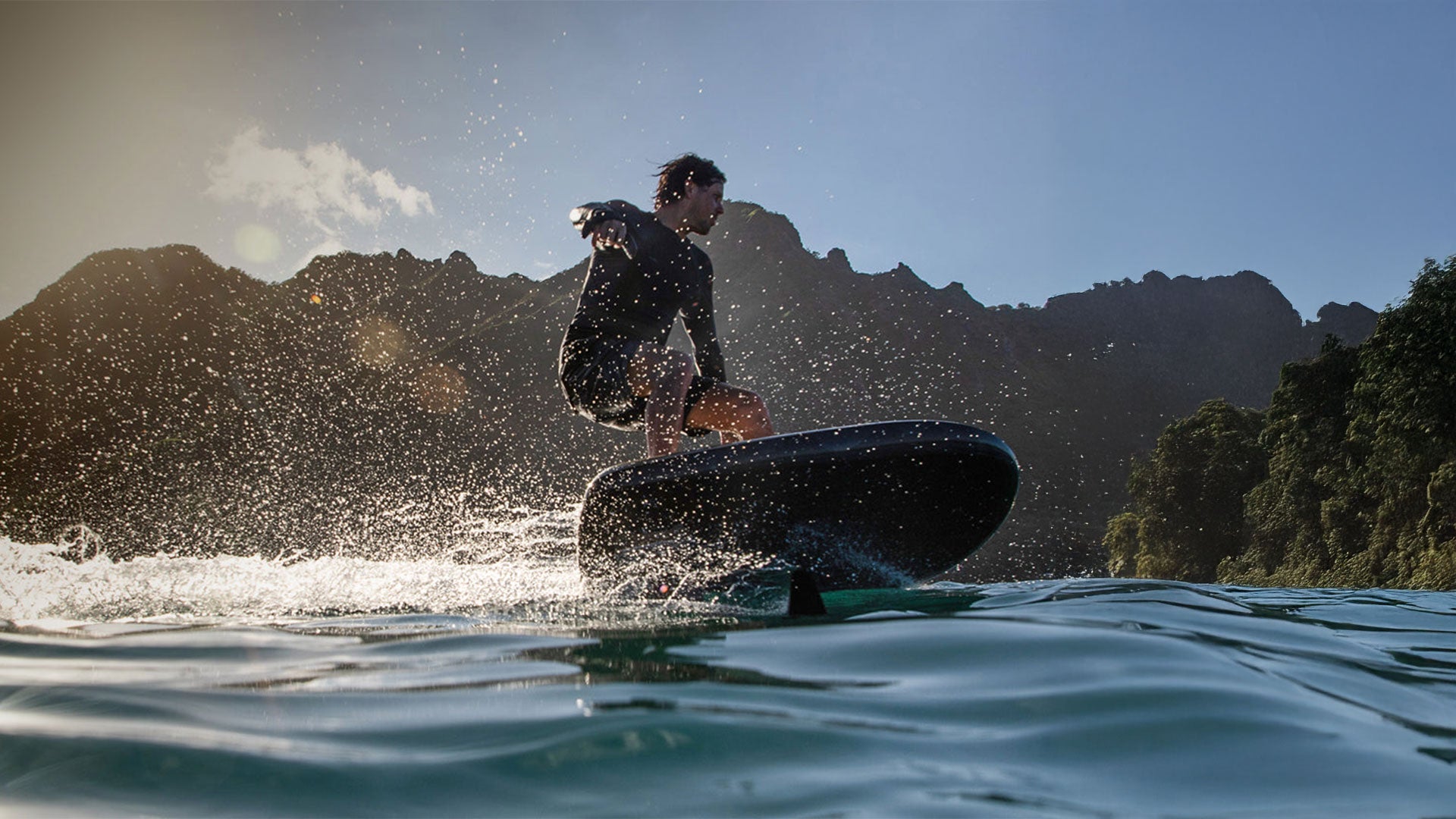 Ein Mann spritzt mit seinem Fliteboard Wasser in die Luft, während er eine steile Kurve foilt.