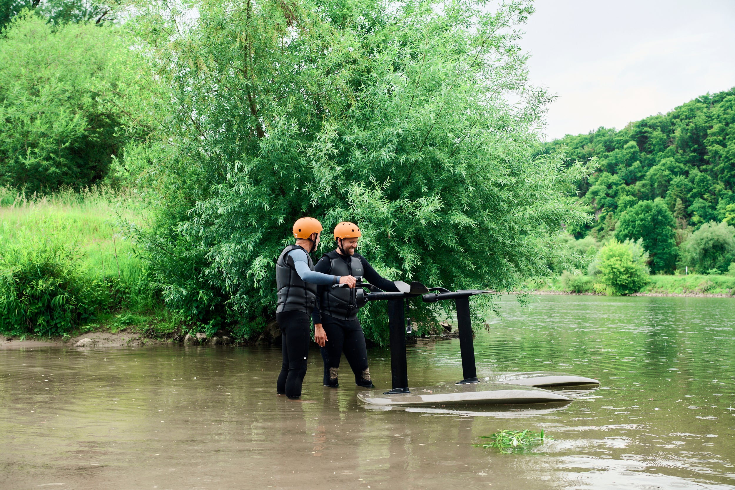 Zwei Personen stehen neben ihren Fliteboards in einem Fluss in Deutschland.