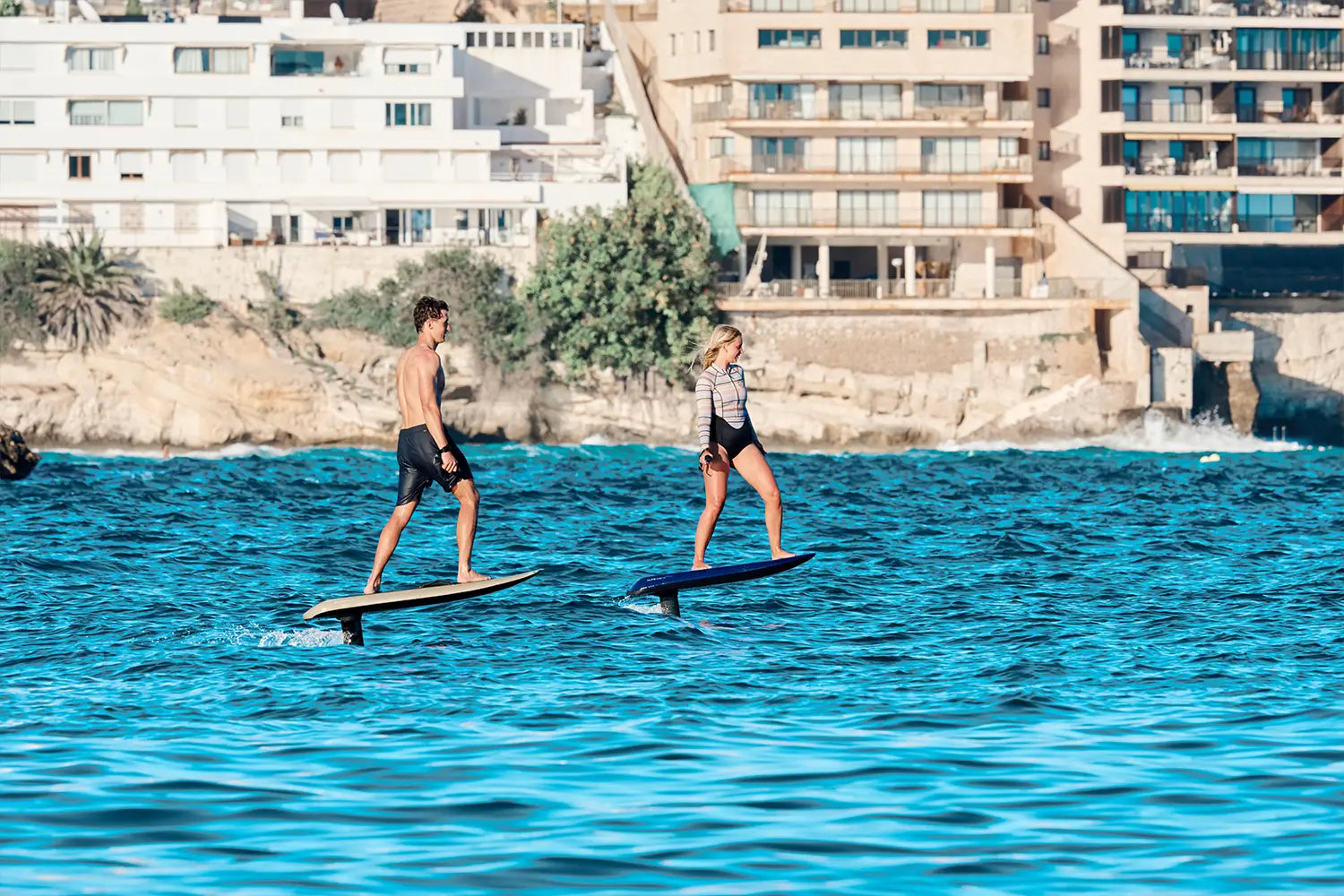 Ein Mann und eine Frau fliegen beide mit einem Fliteboard über das Wasser auf dem Meer.