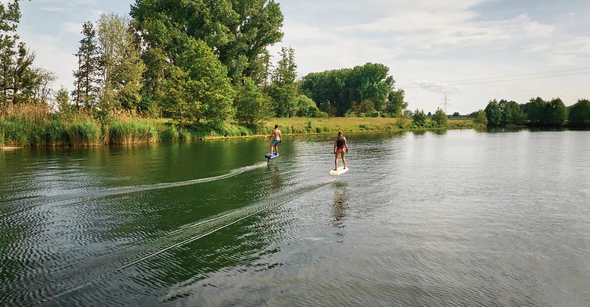Zwei Personen efoilen auf einem Fliteboard auf einem Fluss in Deutschland.