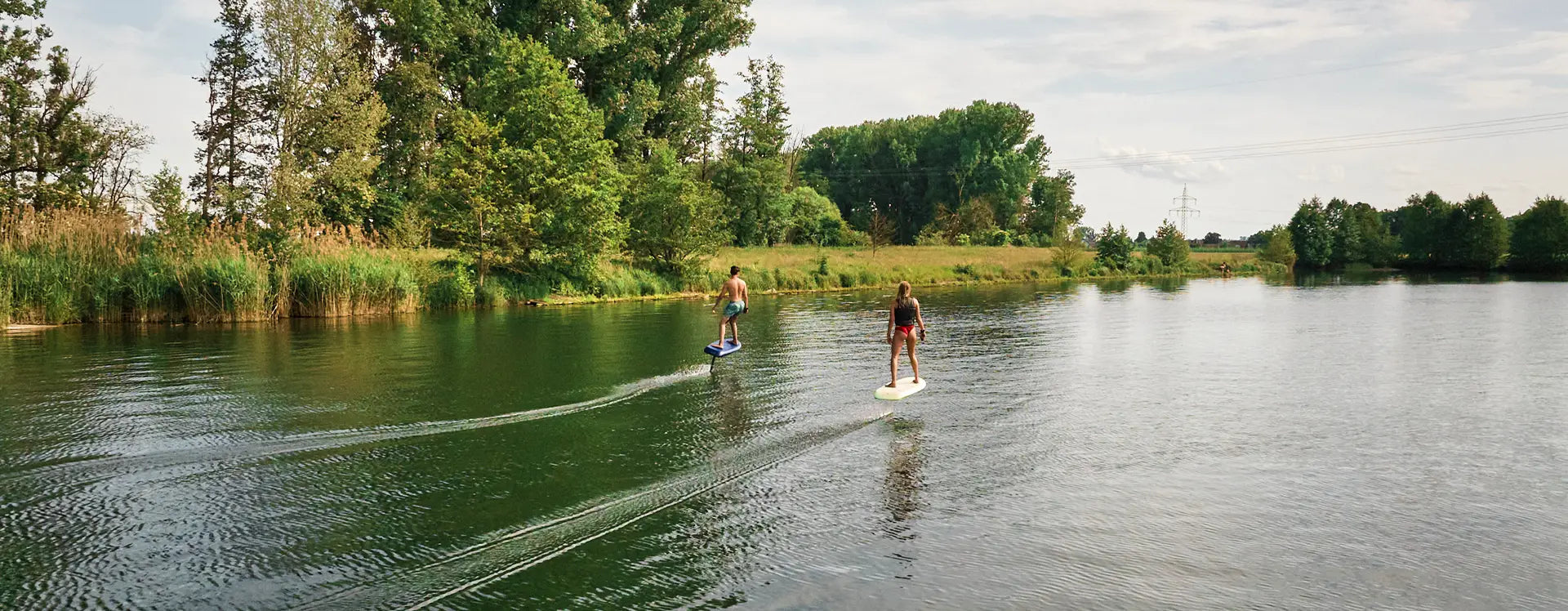 Zwei Personen efoilen auf einem Fliteboard auf einem Fluss in Deutschland.