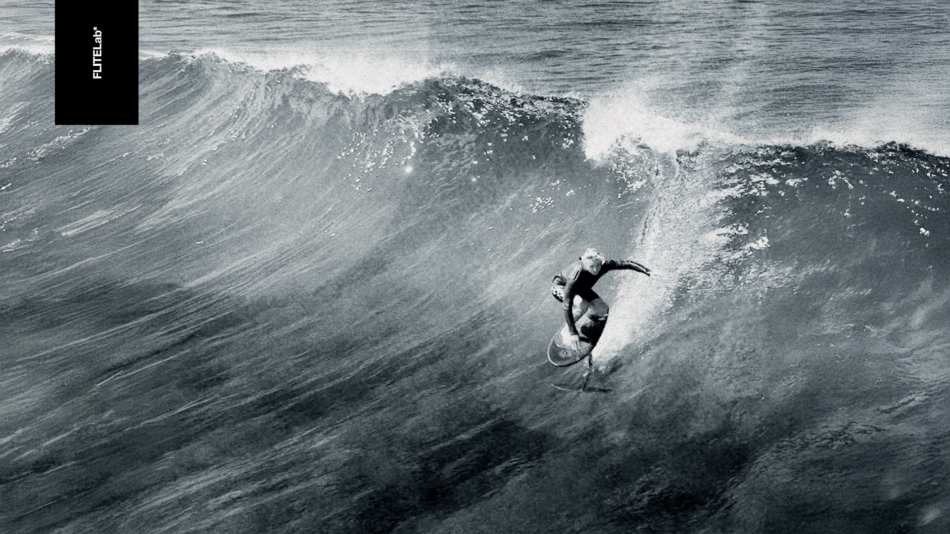 Schwarz-Weiß-Foto eines Surfers, der mit FliteLab auf einer Welle reitet.