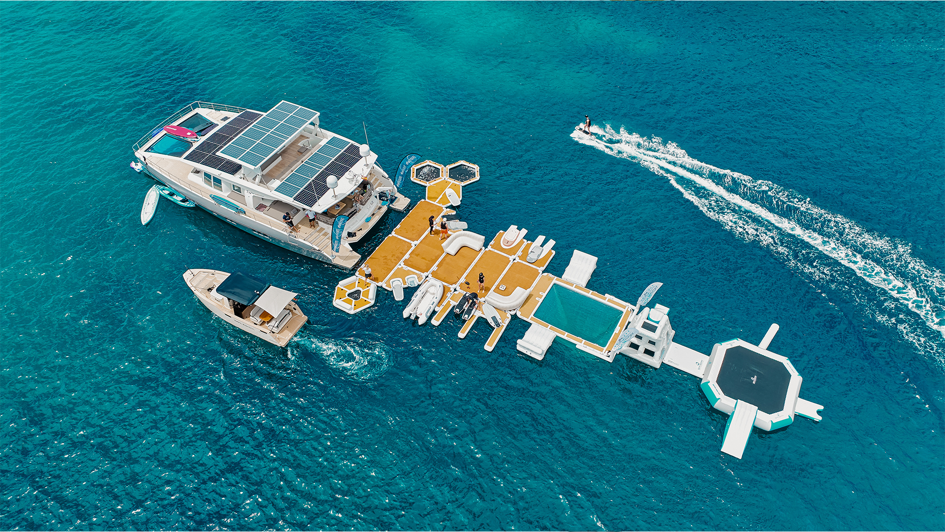 Von oben sieht man eine Jacht auf dem Meer, an der verschiedene Yachtbeach hängen.